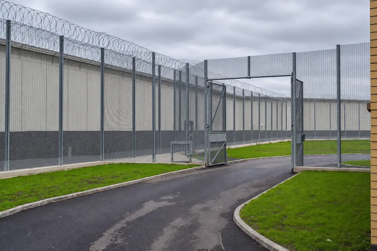 Security mesh fence beside a road with grass on the opposite side