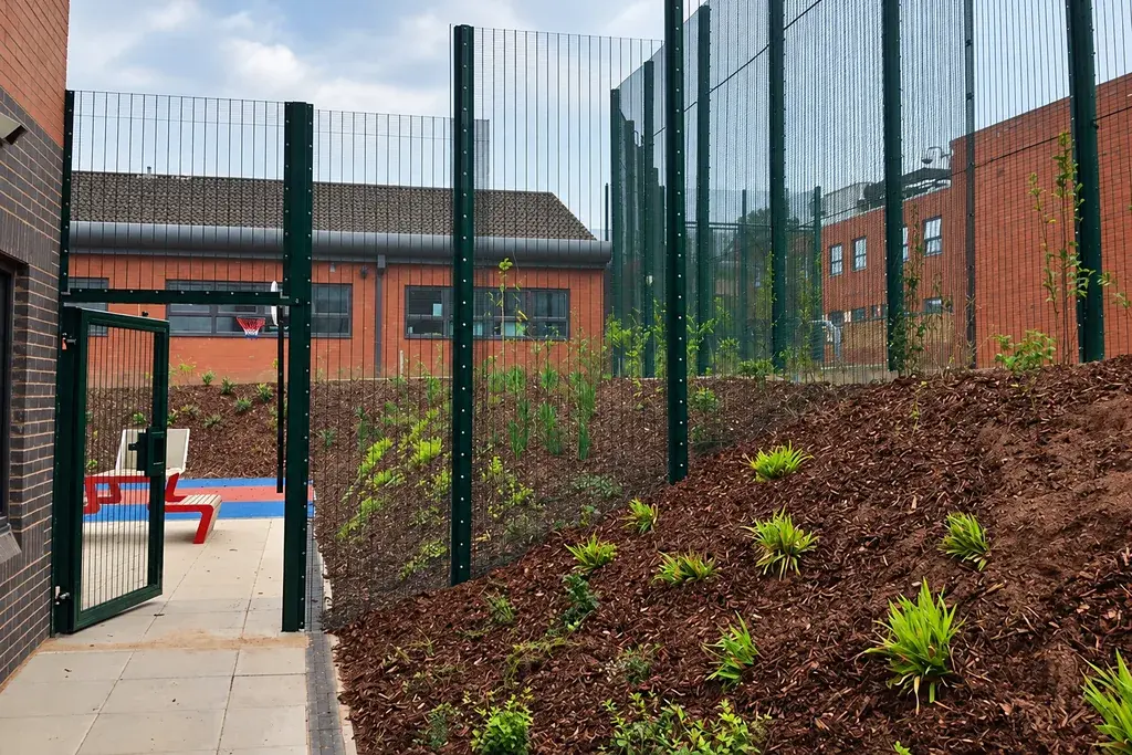 Security mesh fence and gate beside landscaped ground