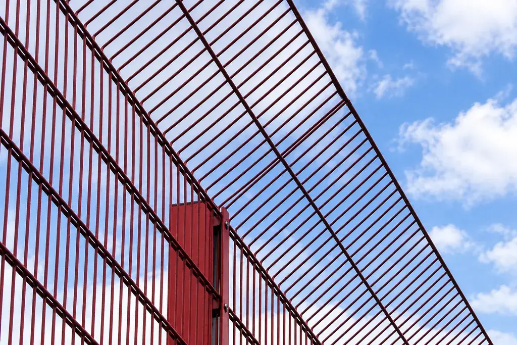 Inclined welded mesh topping fixed to a fence post