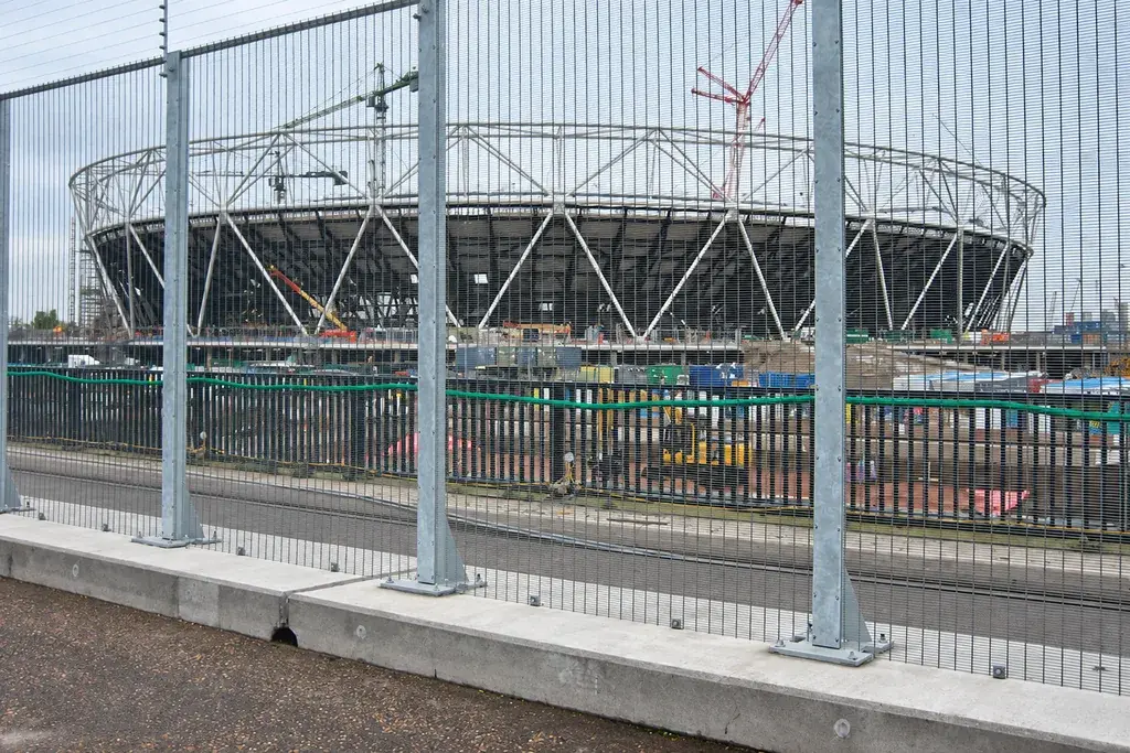 Installed security mesh fence panels and posts beside a stadium