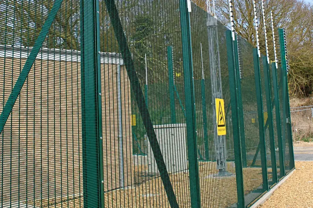 Green security mesh panels meeting a series of fence posts