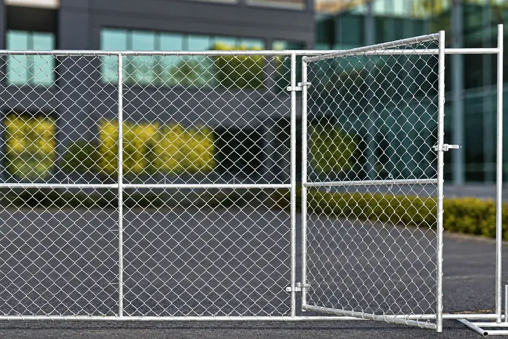 Temporary chain link gate between freestanding mesh panels