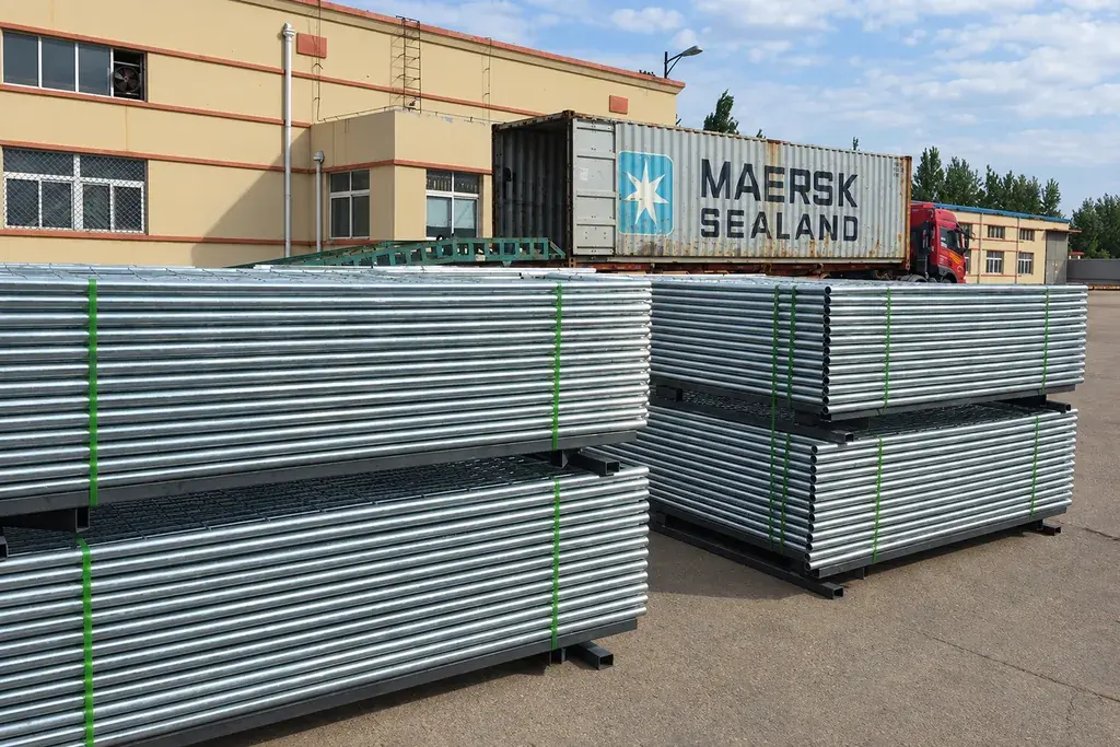 Bundled metal fence components staged near a shipping container