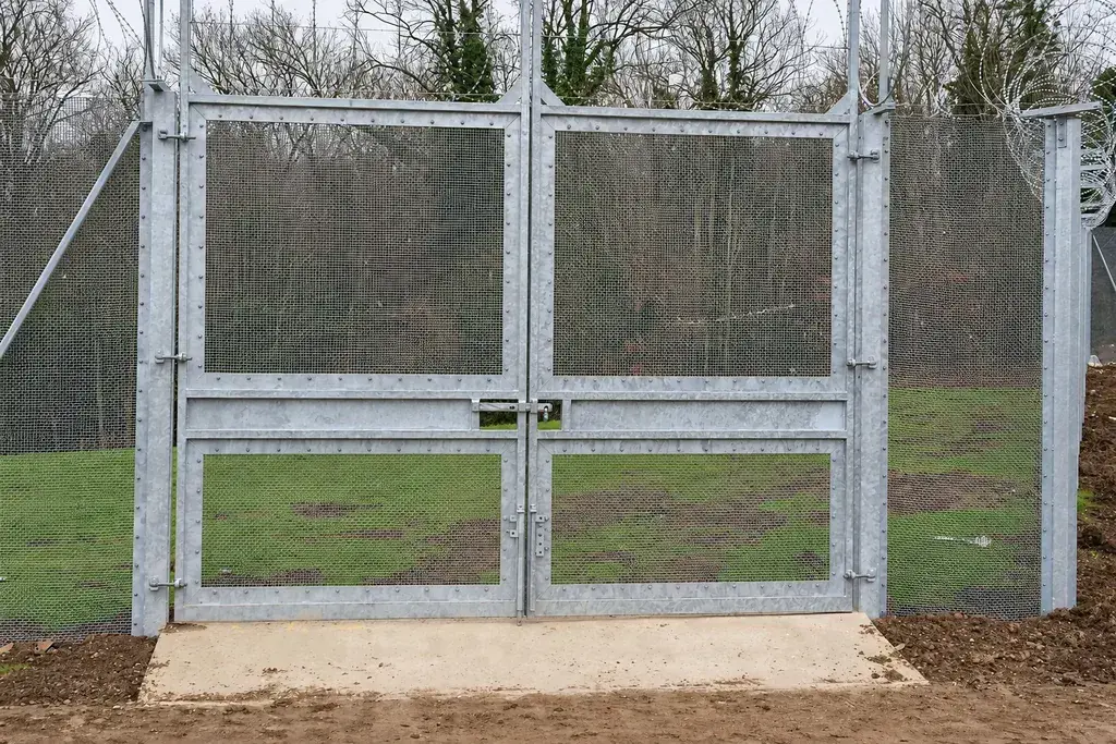 Double leaf security mesh vehicle gate between fixed fence sections