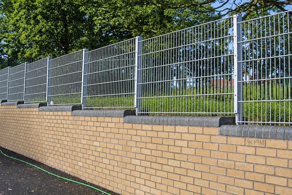 Double wire mesh fence installed above a low brick wall