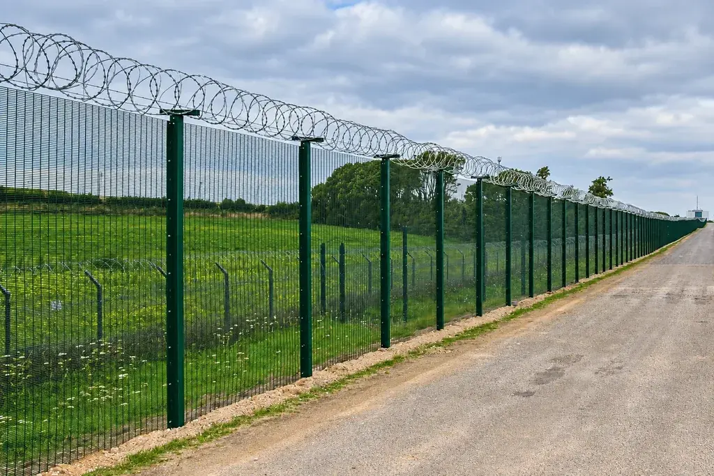 Close mesh security fence beside a long service road