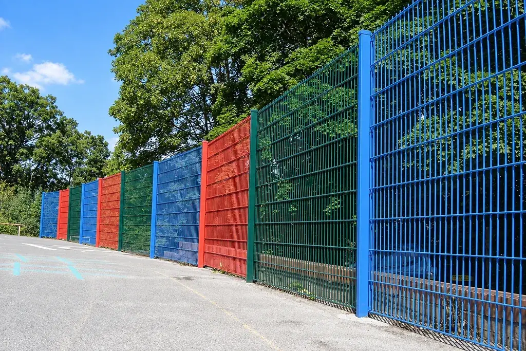 Repeated mesh fence panels and posts along a paved perimeter