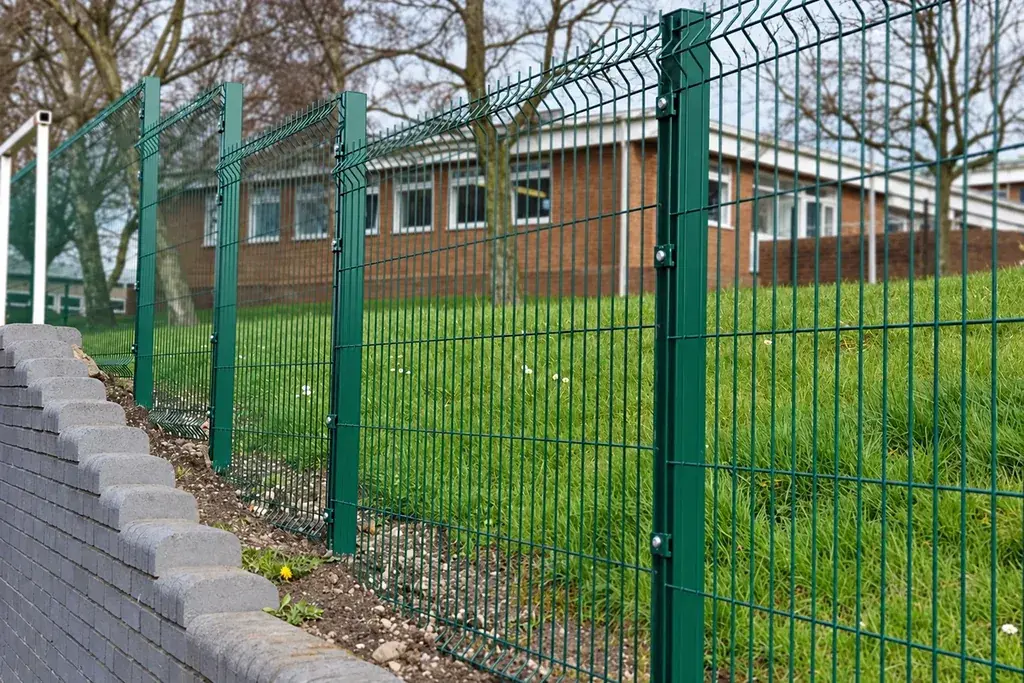 Green profiled mesh fence with repeated V bends along several panels