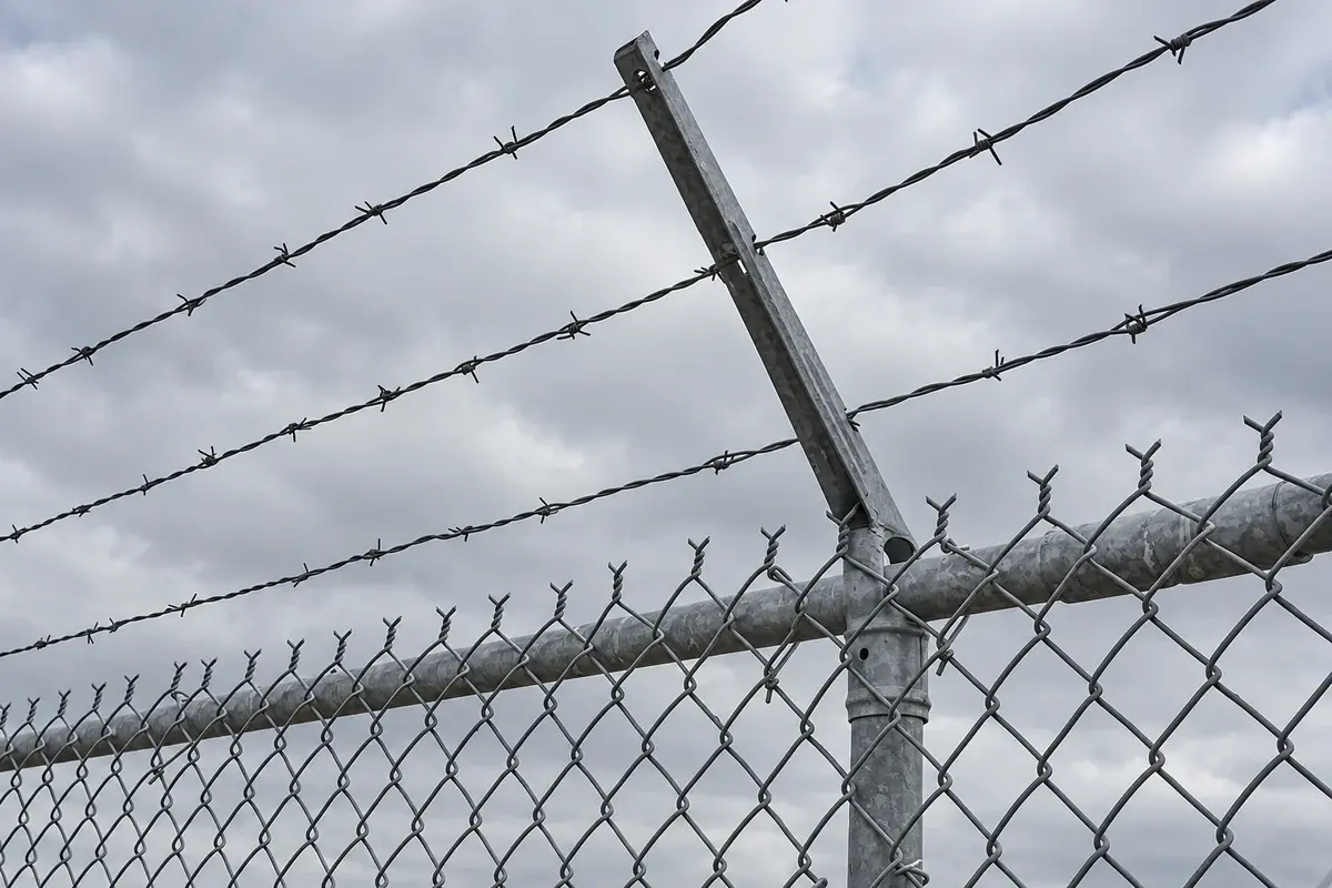 Close view of chain link fabric connected to a round fence post