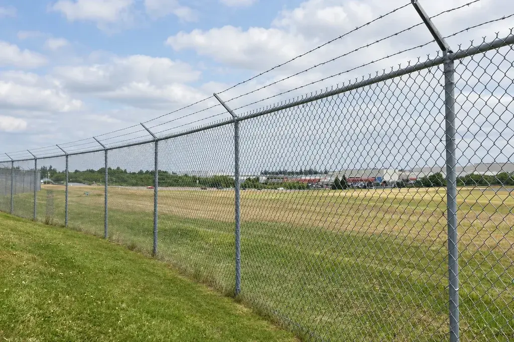 Galvanised chain link fence run with steel posts and barbed wire
