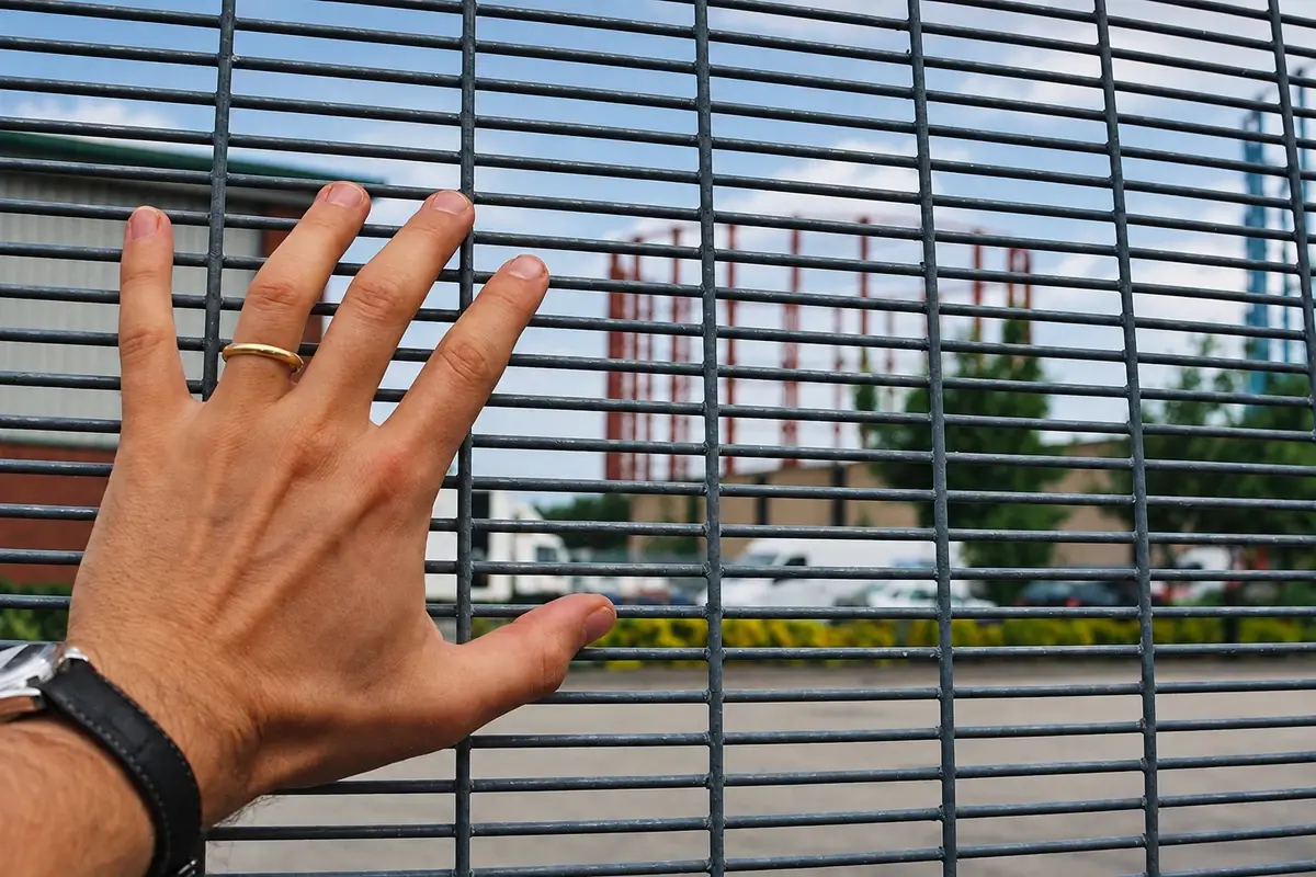 Hand beside a close aperture welded security mesh panel