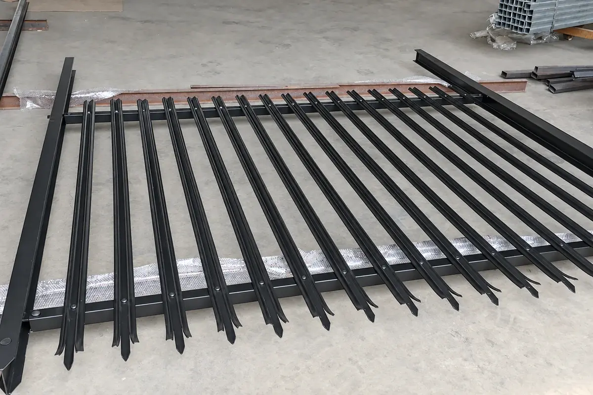 Palisade fence panel laid out on a workshop floor, showing individual pales and rails