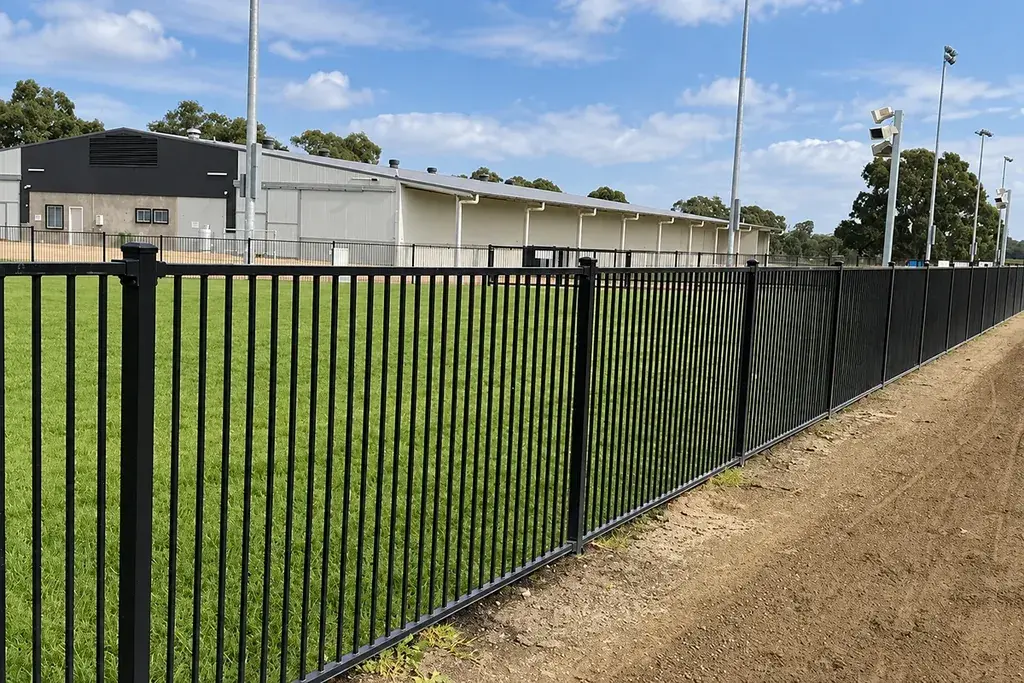 Black steel fence with evenly spaced vertical bars along a site boundary