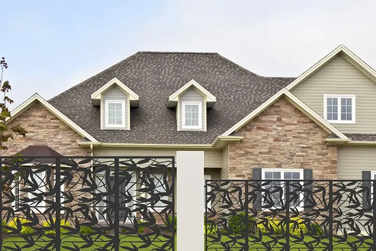 Dark laser-cut metal fence panels with a repeating branch pattern between posts