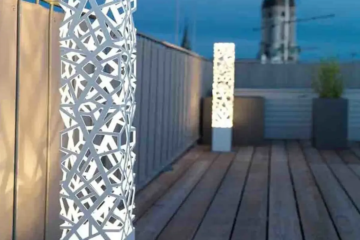 Decorative laser-cut metal screen panels viewed along an outdoor walkway