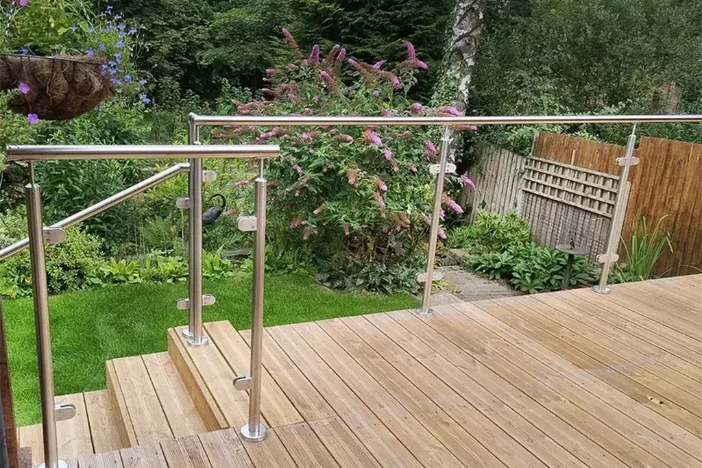 Stainless steel posts and handrail supporting glass panels beside a timber deck