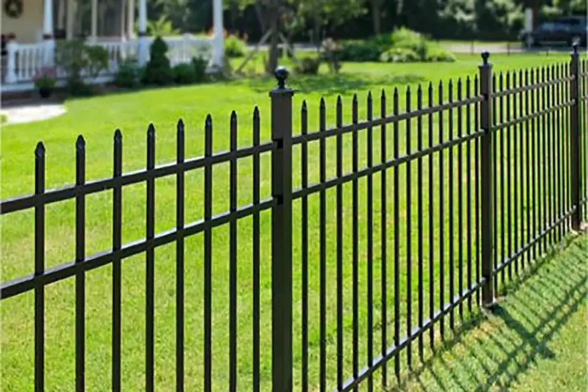 Black spear-top metal fence with rails angled along a sloping lawn