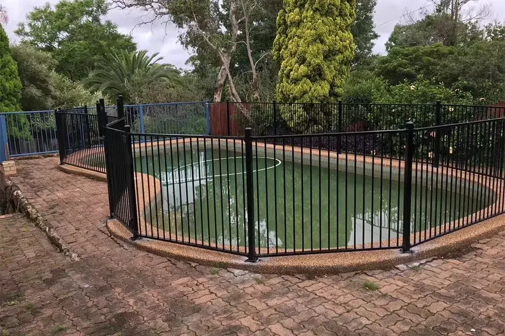 Black metal fence around a curved outdoor swimming pool