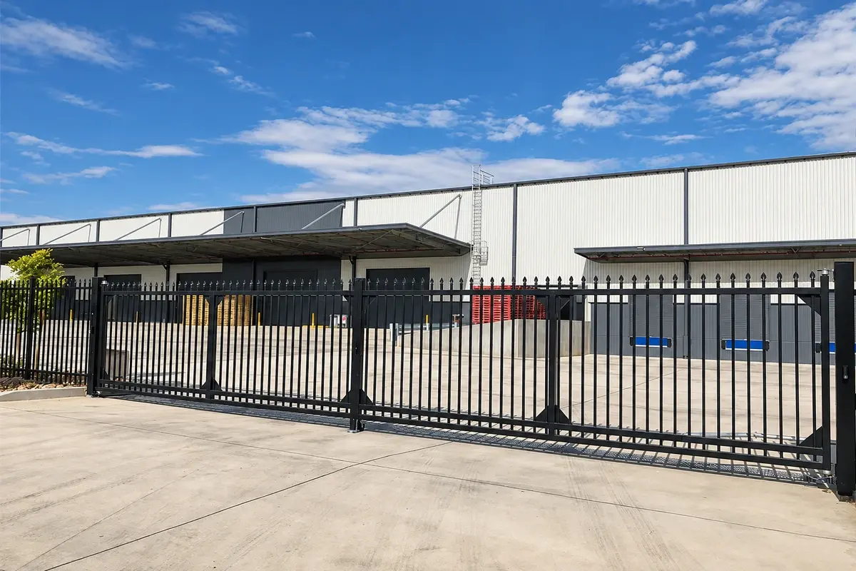Black tracked sliding gate across a paved site entrance