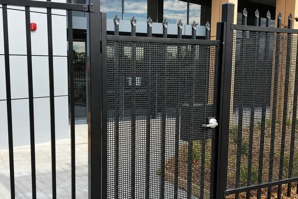 Black single-leaf pedestrian gate between metal fence posts