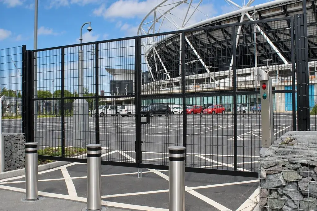 Double-leaf black mesh vehicle gate across a paved entrance