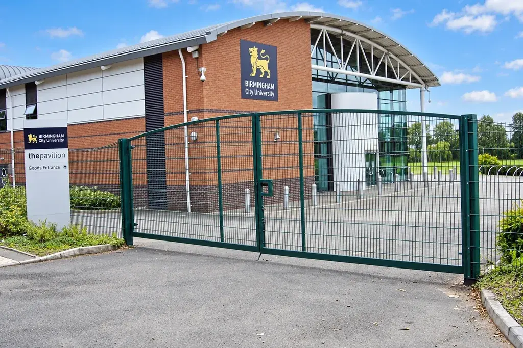 Green double-leaf twin-wire mesh gate at a paved entrance