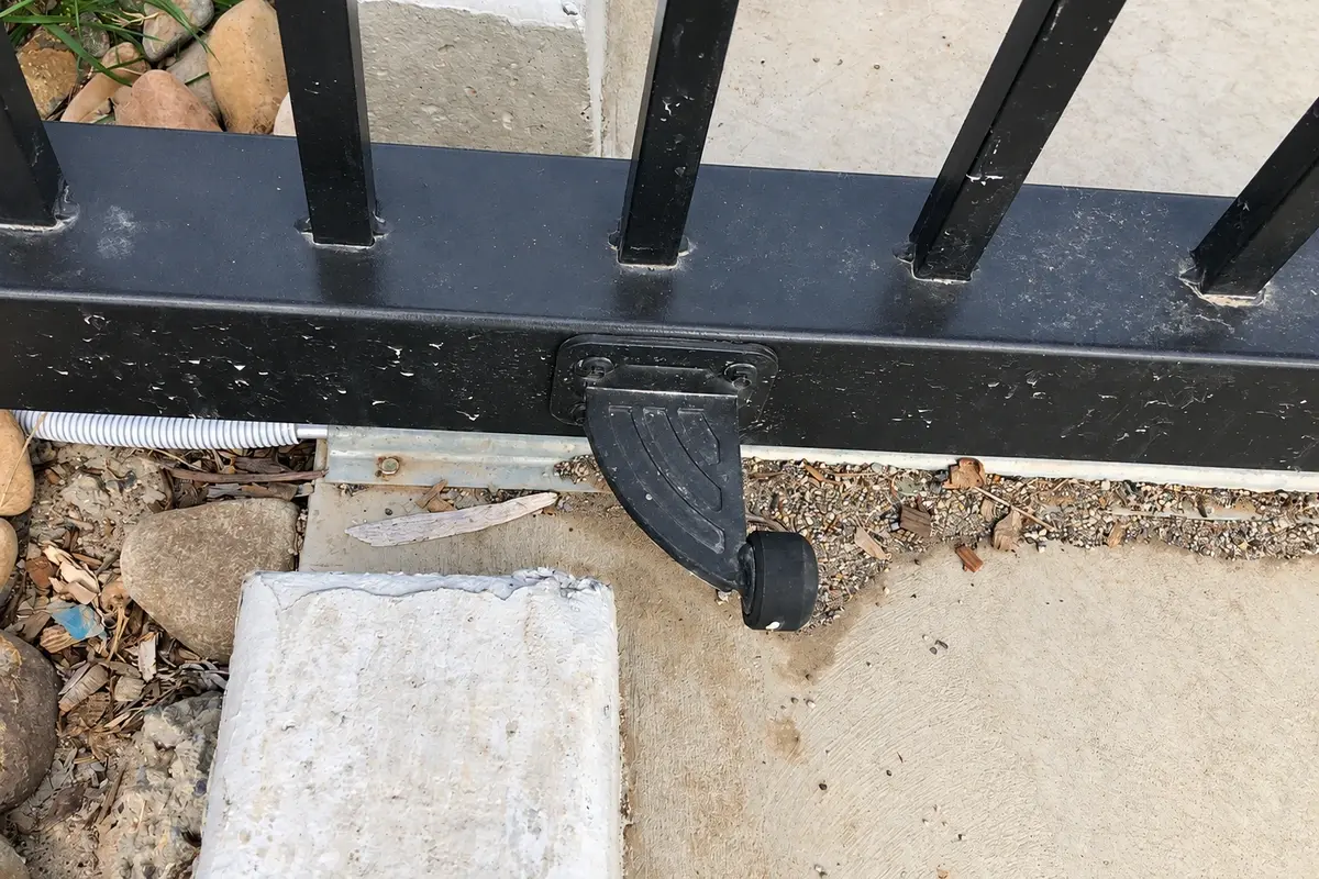 Metal end-stop component fixed beside the lower frame of a sliding gate