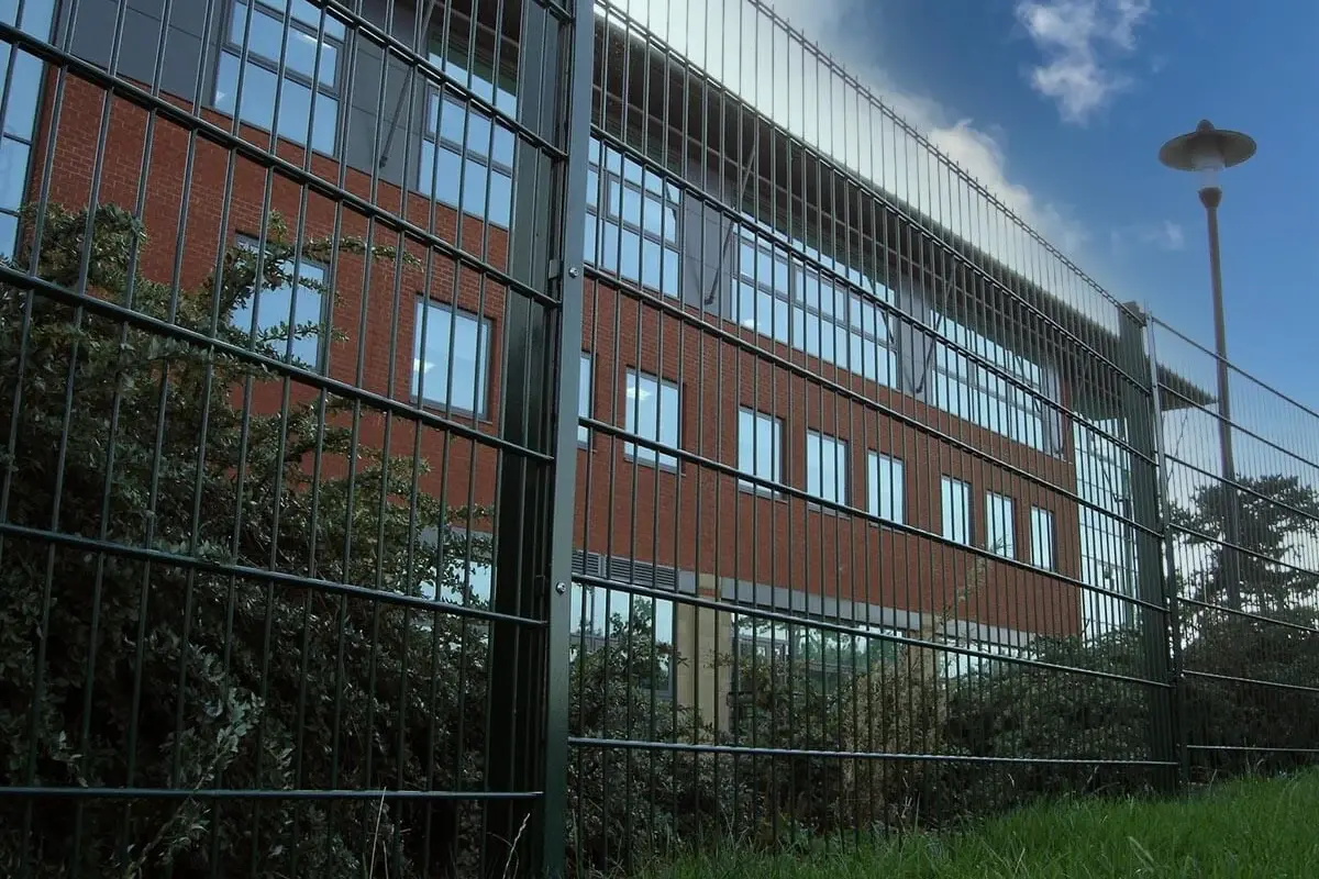 Straight run of mesh fence panels and posts beside a building
