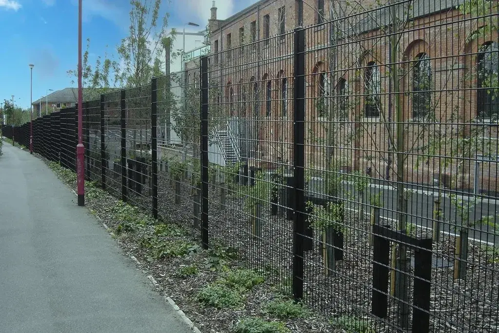 Long straight run of black mesh fencing with repeated line posts