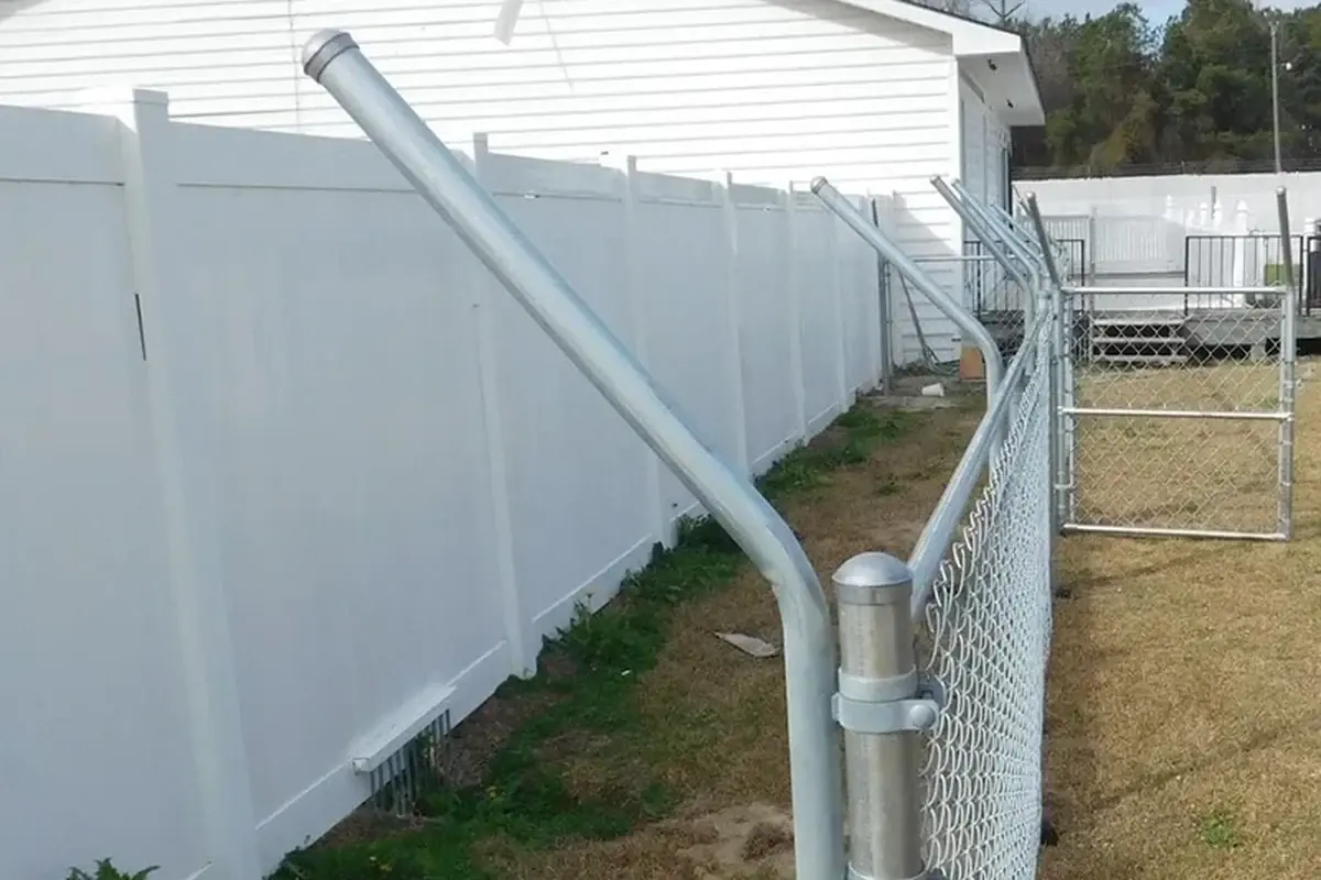 Angled metal extension attached to a fence post beside a white boundary fence