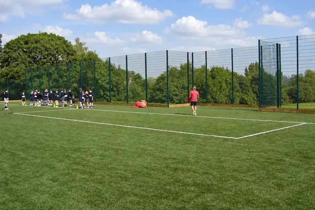 Tall mesh fencing behind a grass sports field