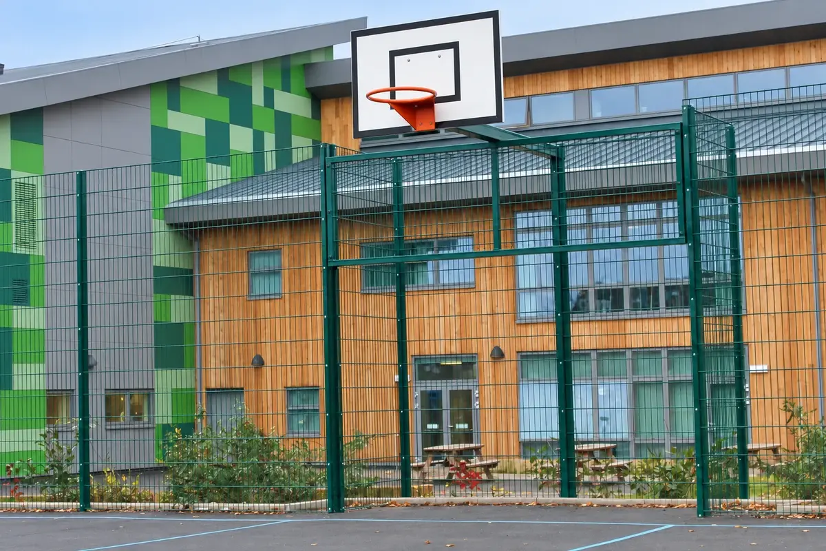 Goal end sports mesh fence beside a court with a recessed goal