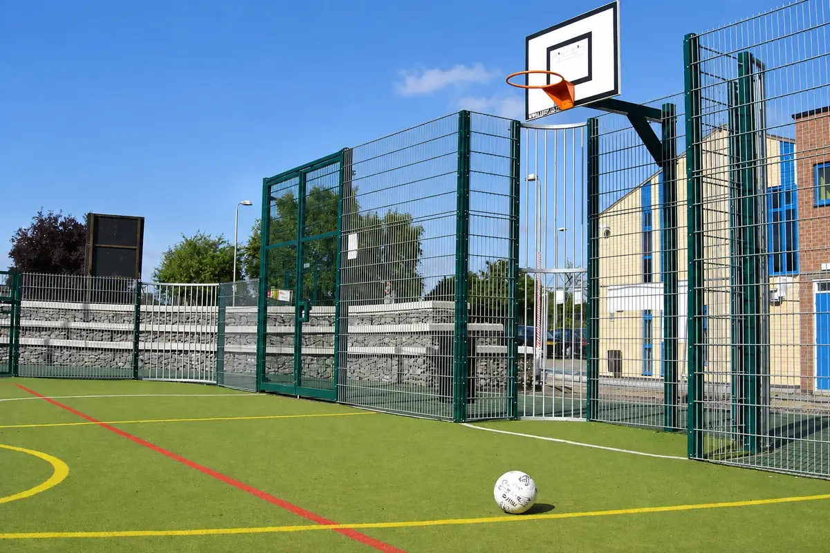 Fenced multi-use court with basketball hoop and goal