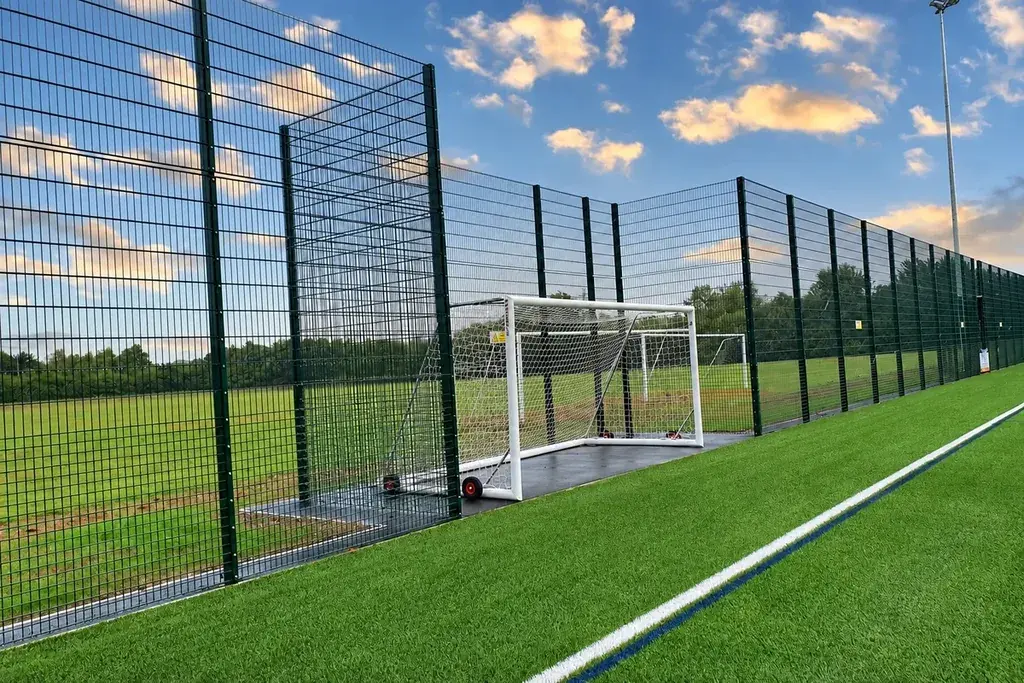 Recessed football goal within a tall sports mesh boundary