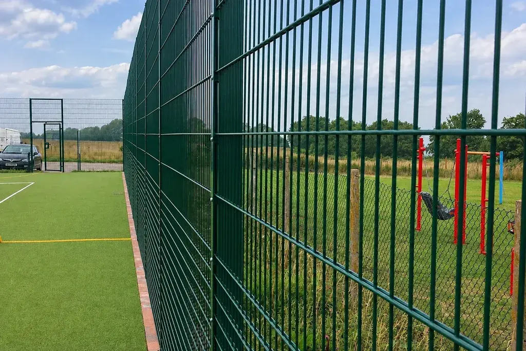 Close view along a sports mesh fence beside a playing field