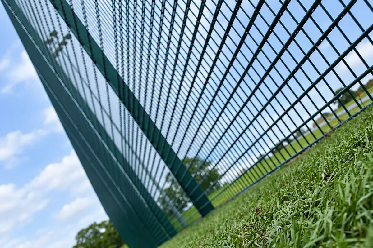 Upward view through tall sports mesh and its supporting posts