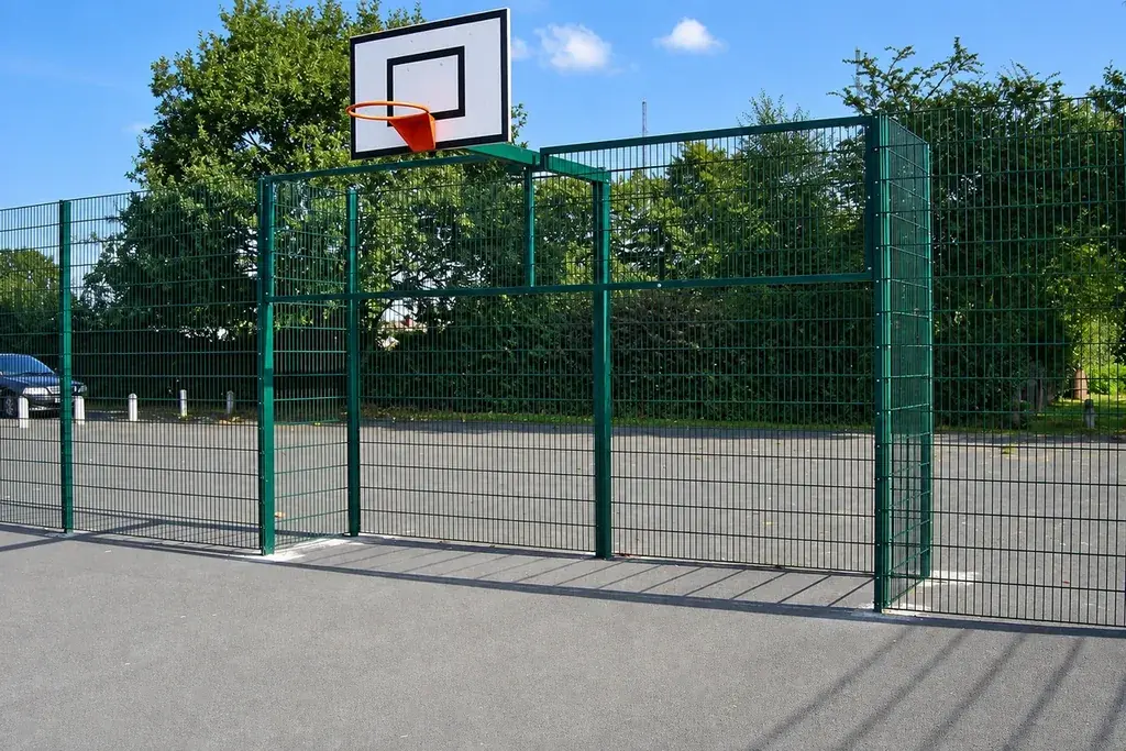 Basketball backboard beside a tall mesh sports enclosure