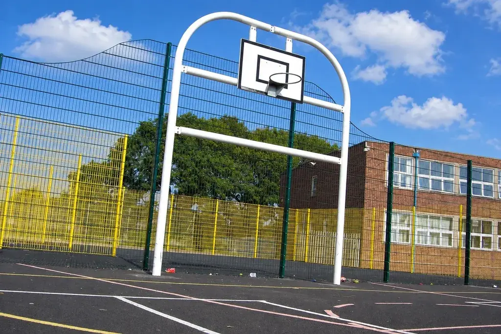 Outdoor basketball court with a hoop and mesh boundary