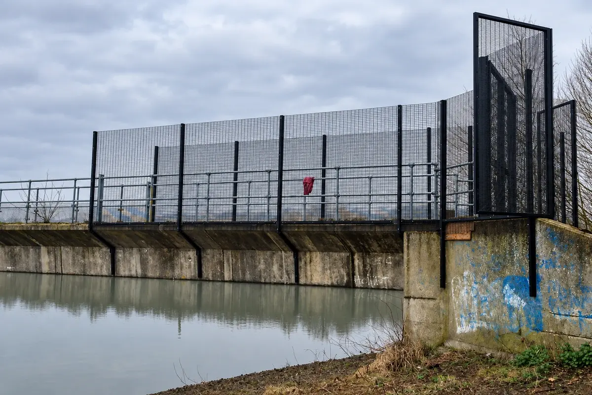 Tall metal mesh fence around a utility site
