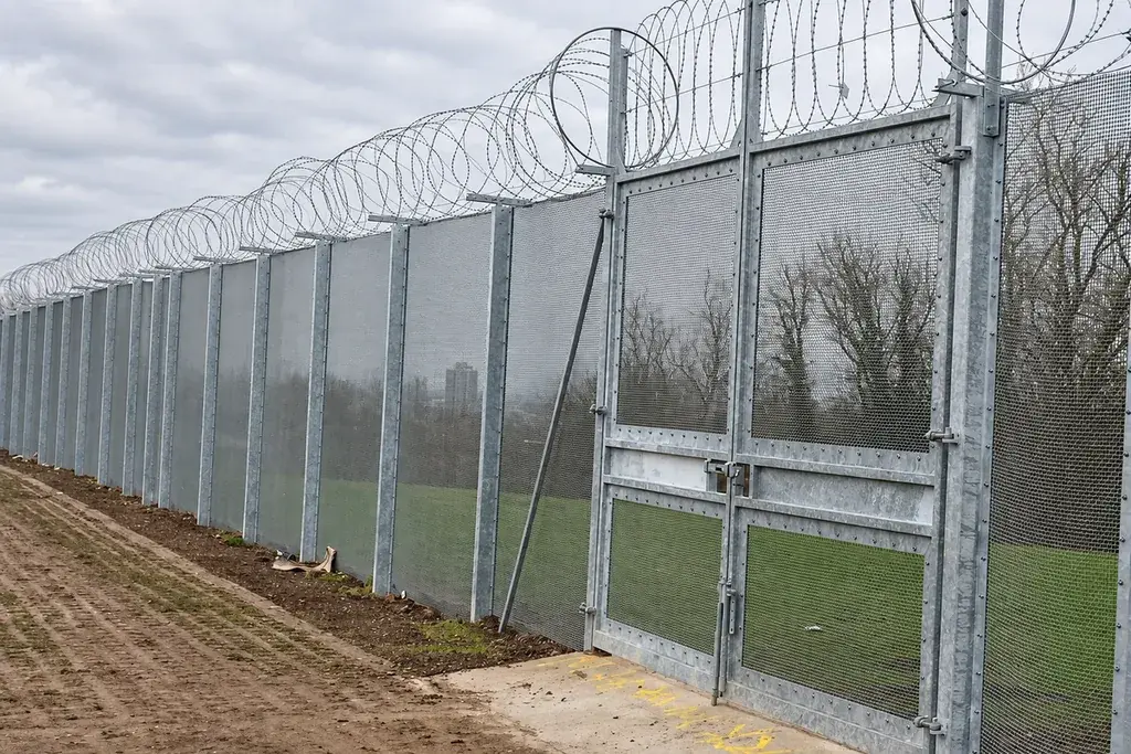 Tall metal mesh vehicle gate within a matching perimeter fence