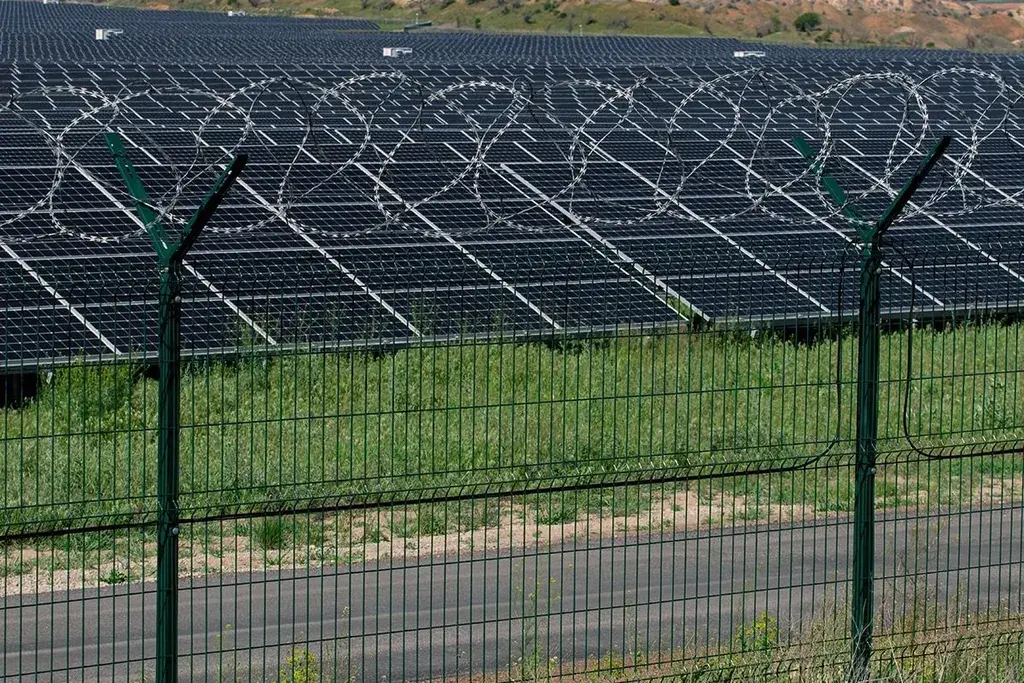 Metal security fence around a solar array in an open landscape