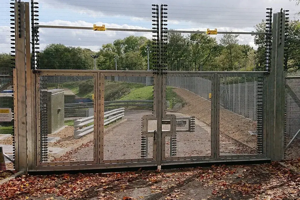 Wide metal mesh vehicle gate within a perimeter fence