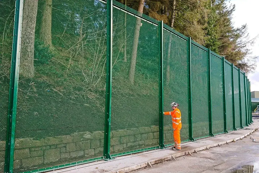 Green close-spaced mesh security fence along a site boundary