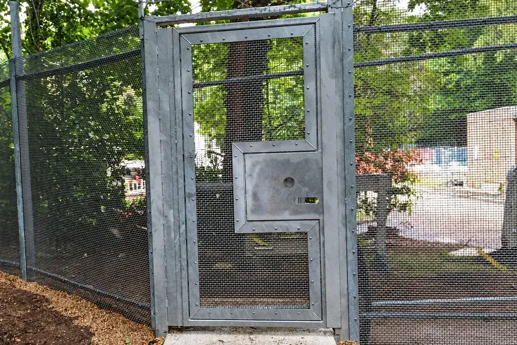 Grey metal mesh gate with framed leaf and adjacent fence panels