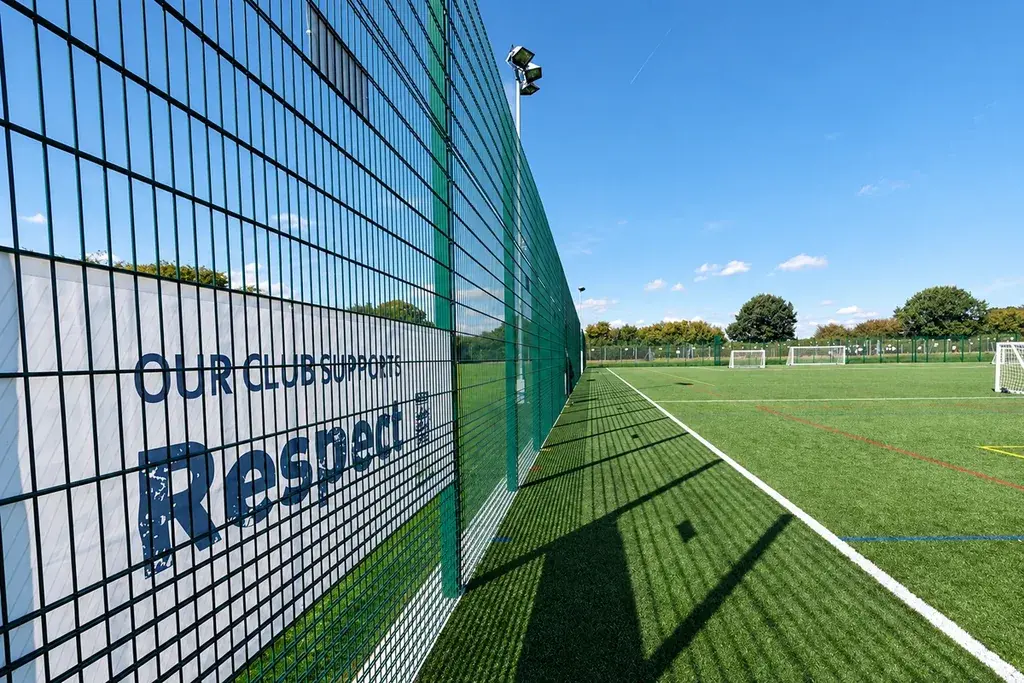 Tall green mesh fence beside an outdoor school sports court