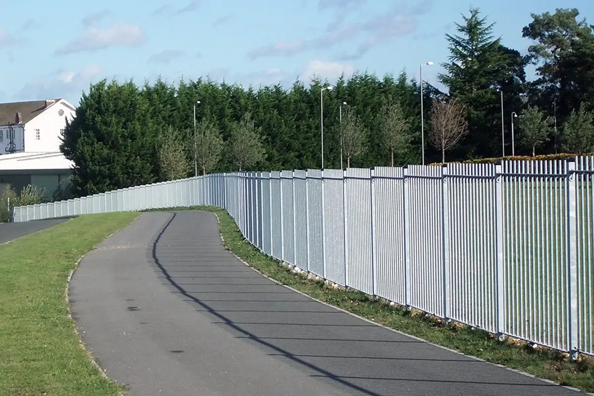 Long run of white vertical bar fencing beside a paved path