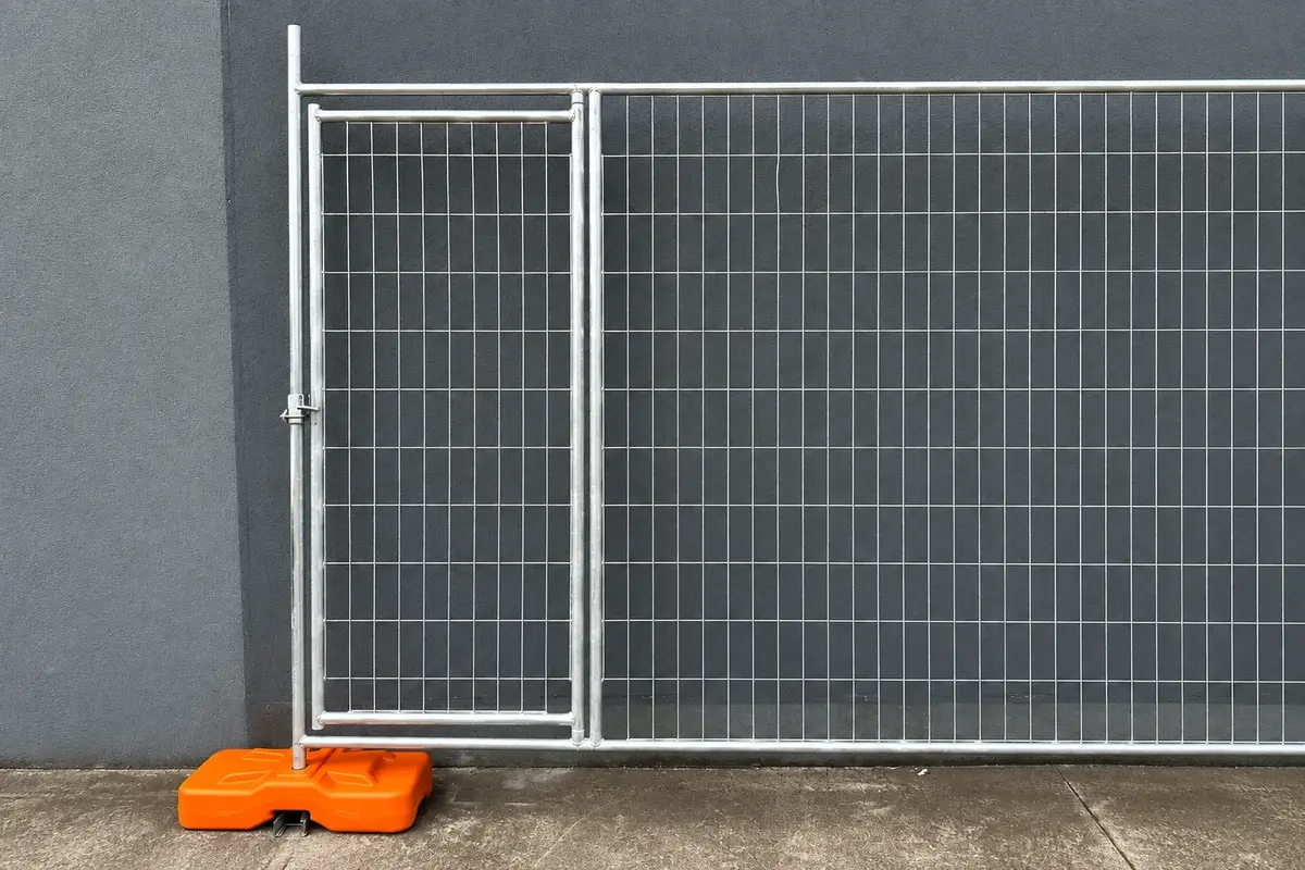 Narrow temporary mesh gate connected to a matching panel with an orange weighted base