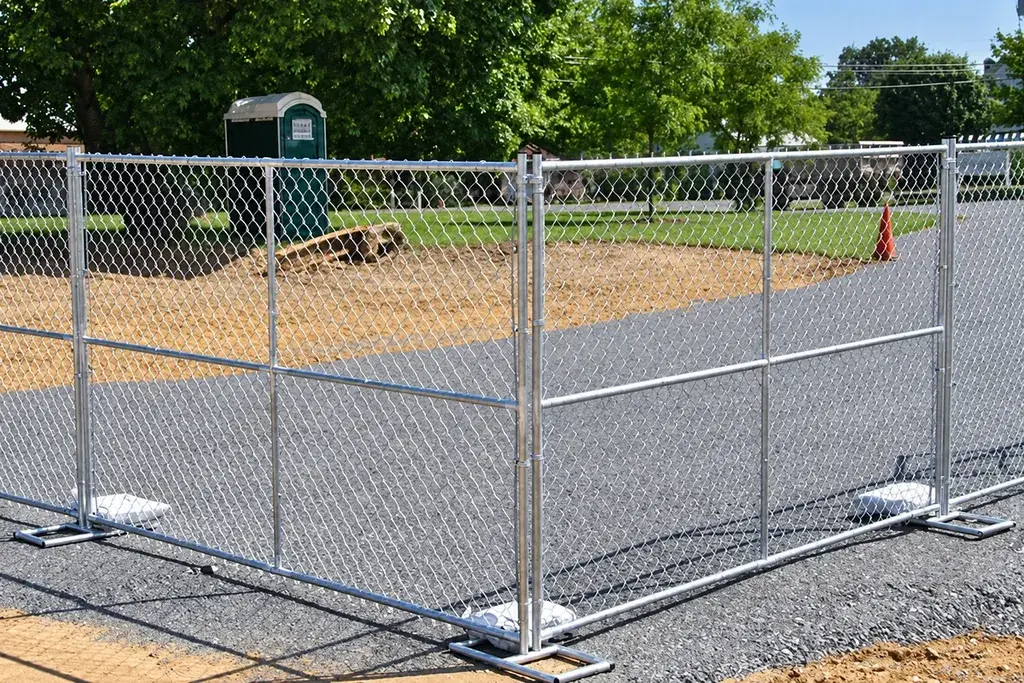 Framed temporary chain link panels with metal feet beside a paved site