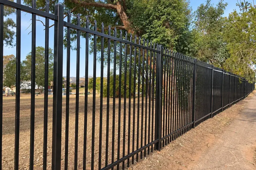 Long run of fixed black steel fencing beside a landscaped path