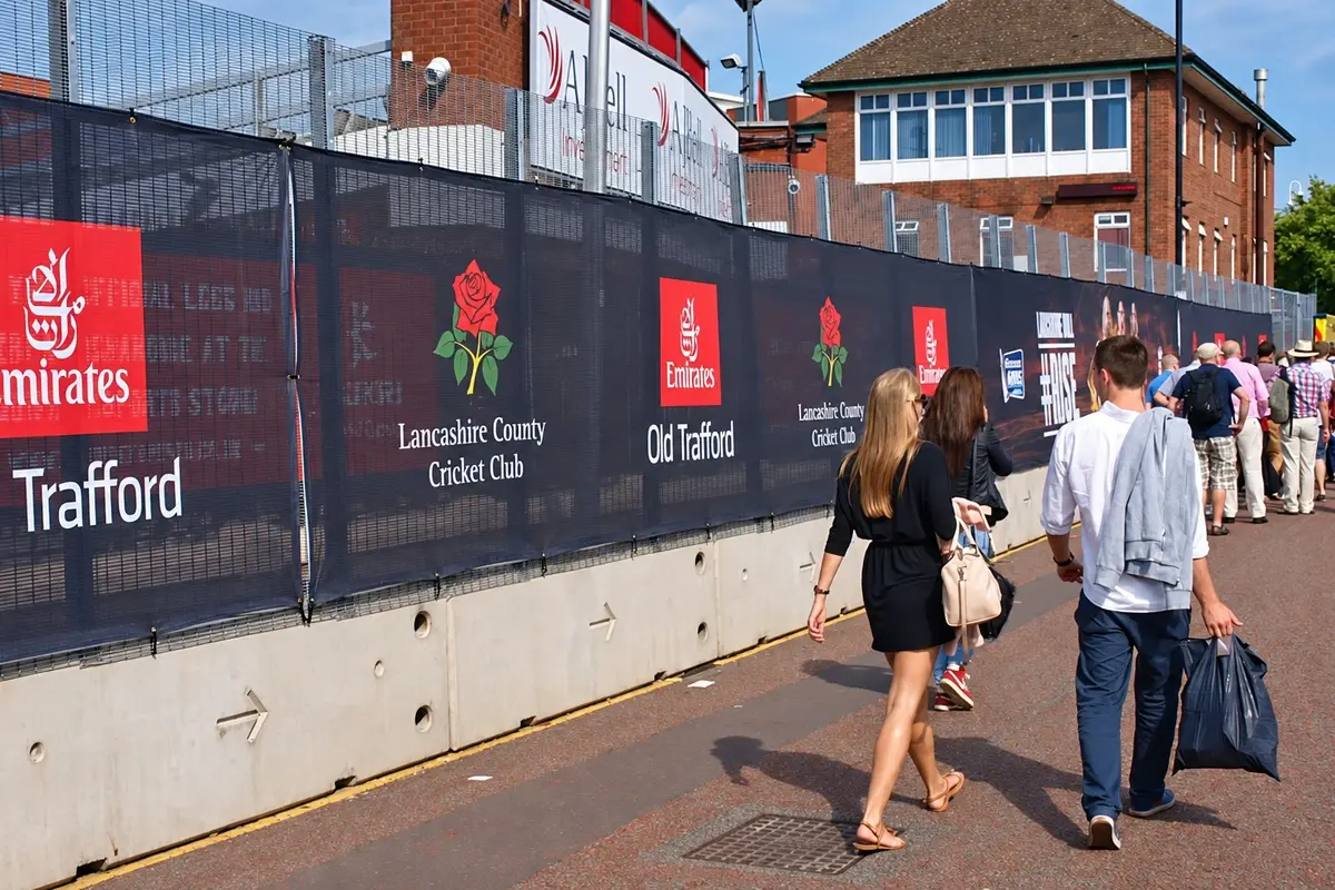 Temporary construction fence covered with dark advertising graphics beside pedestrians